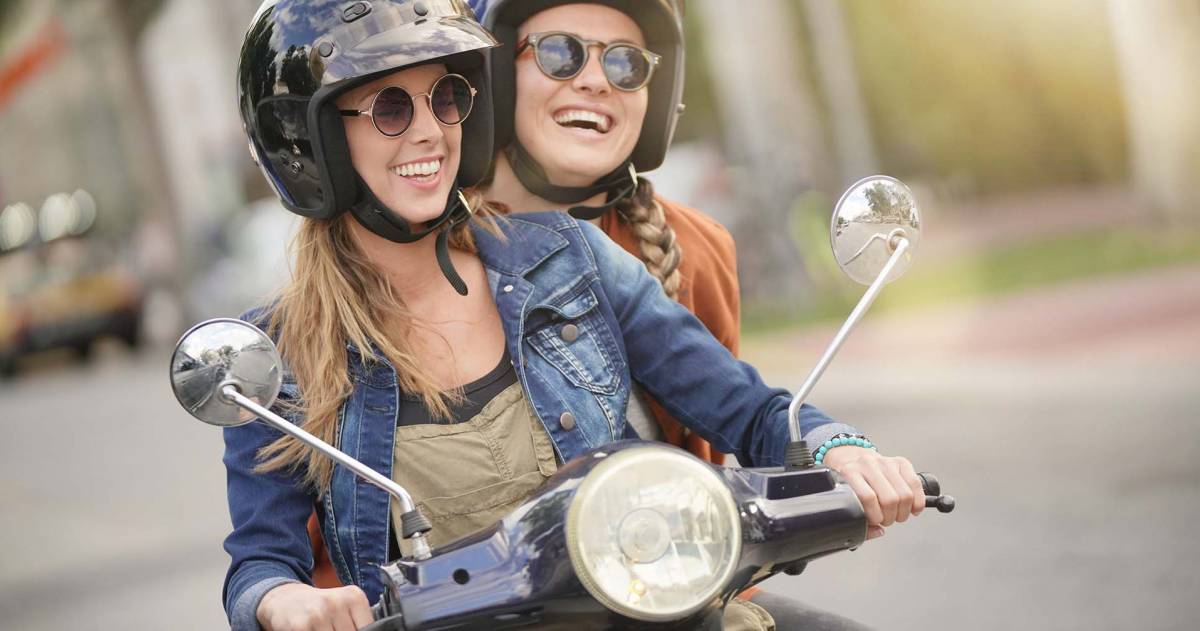 Twee jonge vrouwen rijden samen op een scooter